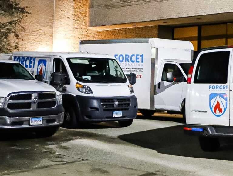 Force1 restoration service vehicles parked outside building
